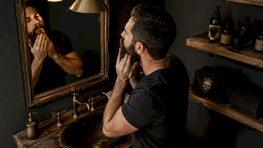 Man applying beard oil in bathroom mirror