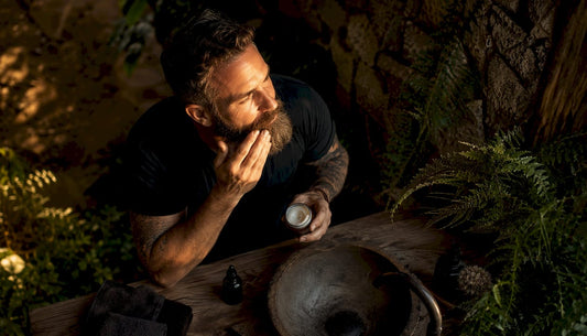 Man applying coconut oil to beard in bathroom