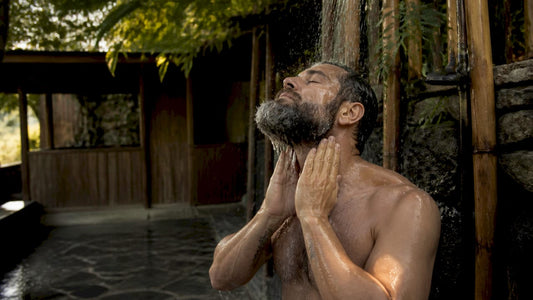 Man rinsing beard under rustic shower